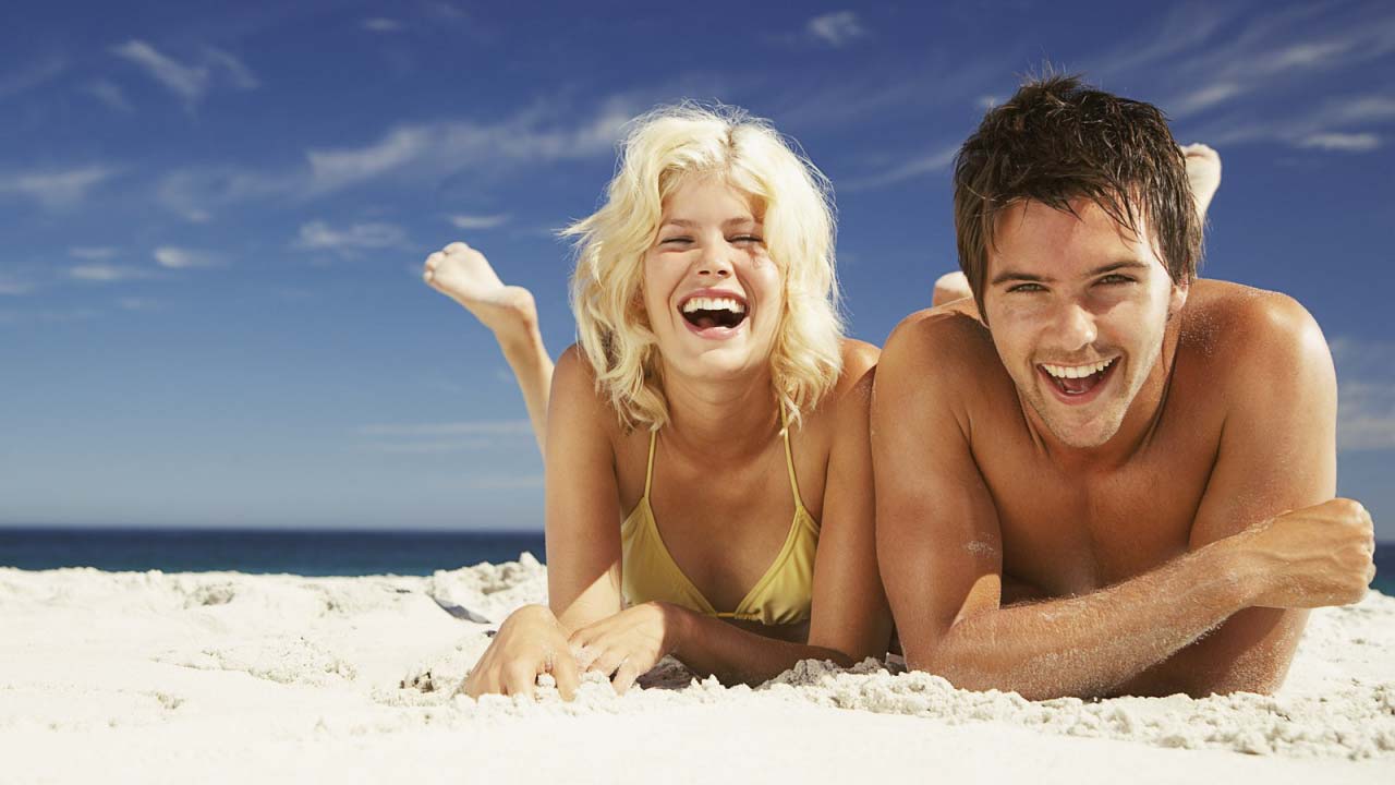 Пока муж на пляже. Пара загорает на пляже. Пара на море. Пляжные люди. Мужчина и девушка смеются.